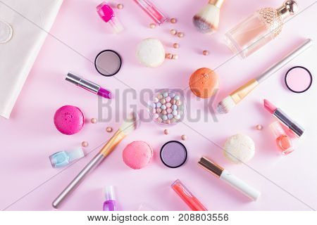Make up products and macaroons on pink background