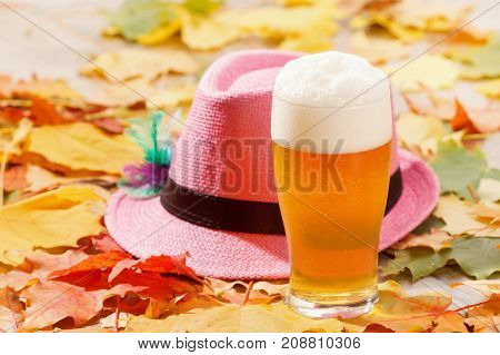Beer glass pint octoberfest picnic on natural background with hat and autumn yellow leaves