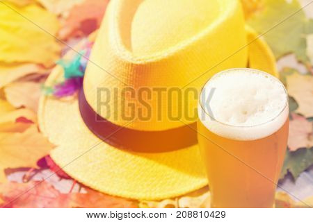 Beer glass pint octoberfest picnic on natural background with hat and autumn yellow leaves