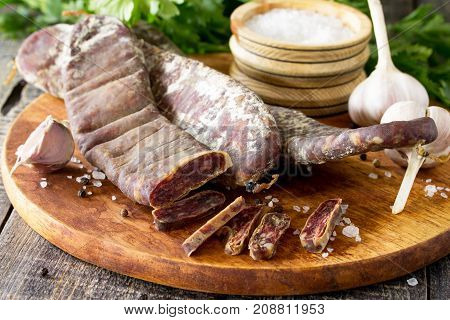 Beef Jerky Smoked Sausage Sudzhuk With Spices And Garlic Is Served On A Cutting Board.