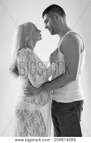 Beautiful pregnant couple in love on the background. Hands of husband on the tummy of his pregnant wife. Young man tenderly stroked pregnant belly of his wife. Husband kissing pregnant belly.