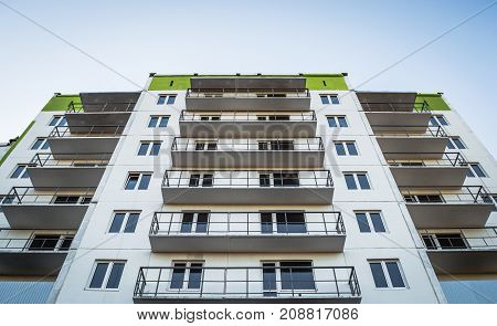 residential building with windows and balconies made of iron, built of concrete slabs painted white