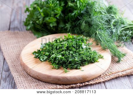 Cutting board with green chopped herbs on the table
