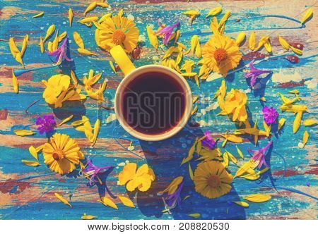 yellow сup with tea or coffee multicolor flowers around