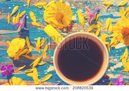 yellow сup with tea or coffee multicolor flowers around
