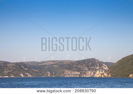 Romanian Wind Farm with Wind Turbines and windmills facing the Danube river in the Iron Gates valley. Due to the heavy winds in the gorges it has been chosen as a spot to develop green energies