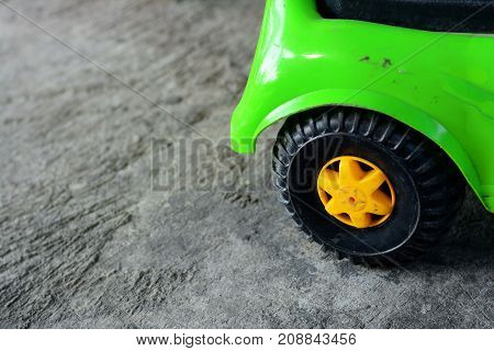 green tpy car with black wheels on rough and dirty cement