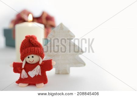 Festive Christmas decoration with tiny doll wooden Christmas tree and candle with copyspace on white