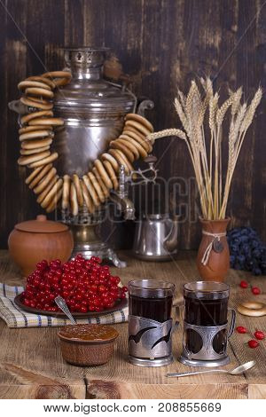 Russian traditional kettle samovar on the wooden table. Black tea bagels red viburnum jam and tea samovar in the rustic style. Russian national tea ceremony