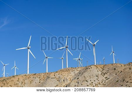 A large group of wind turbines standing along the twentynine palms highway in Southern California, near North Palm Springs
