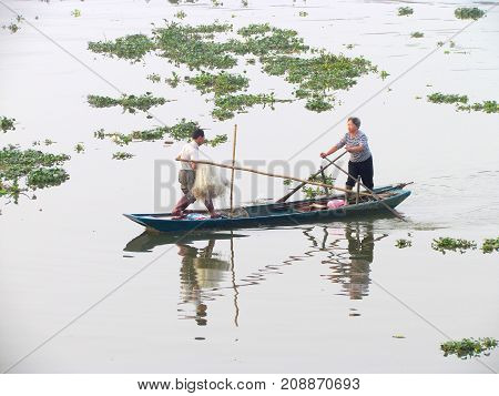 Kaiping Guangdong China, 28 October 2014: Asian fisherman couple with fishing net on small boat on a river with beautiful water at sunrise in rural China
