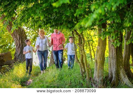 happy family on a walk in a beautiful evening park amicably hold hands and walk along the trail