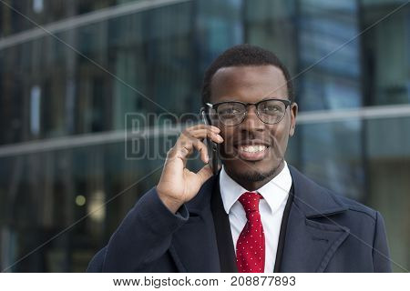 Outdoor Headshot Of African American Businessman Talking On Phone In Street Discussing Important Bus