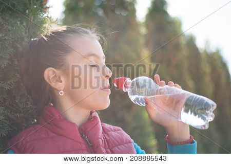 Beautiful girl drinking water after jogging in outdoor. A  beautiful girl is drinking water the hot sun in the park. Healthily concept. Healthy lifestyle concept. copy space. Portrait  beautiful girl