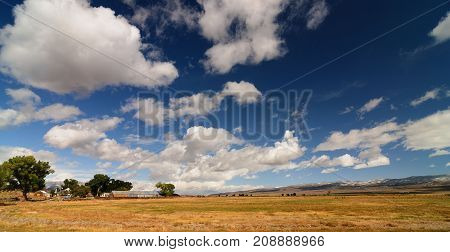 Panoramic American Rural Farmland Countryside Landscape With Blue Cloudyscape and mountains in the distance
