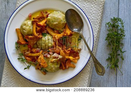 Bread dumplings with chanterelles on a plate with fresh Majoram