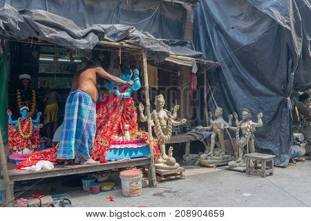 KUMARTULI KOLKATA INDIA - OCTOBER 10 2014 - Artist preparing clay idol to be worshipped as Goddess Kali during Kali Puja Hindu festival of Deepavali or Diwali. Celebtated all over India.