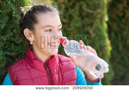 Beautiful girl is drinking water the hot sun in the park. Healthily concept. Healthy lifestyle concept. copy space. Portrait happy smiles beautiful girl . Portrait smiles girl. girl drinking water