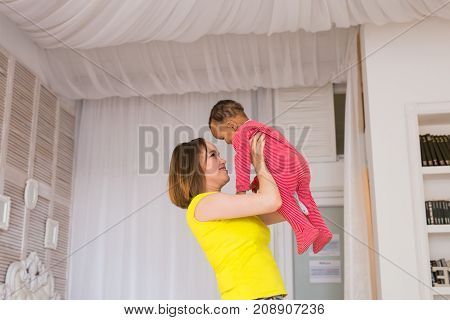 happy family. Mother throws up baby, playing at home.
