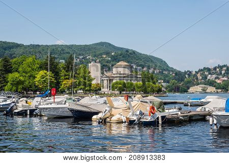 Como Italy - May 27 2016: Yachts and houses along Lake Como in Como town Lombardy region of Italy Europe. Volta Temple (Tempio Voltiano) in the center.