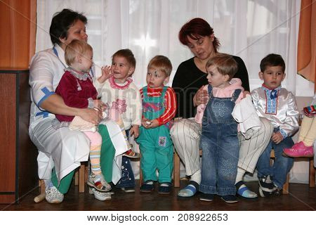 LUTSK UKRAINE - 19 December 2008: Caregiver and little orphan children in an orphanage