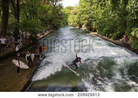 Munich, Germany, June 24, 2017: Surfers practicing their skill on an artificial wave situated on Isar river channel in Englischer garten, Munich central park, on 24th of June, 2017 in Munich, Germany.