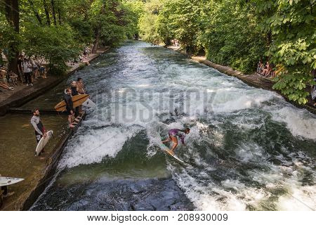 Munich, Germany, June 24, 2017: Surfers practicing their skill on an artificial wave situated on Isar river channel in Englischer garten, Munich central park, on 24th of June, 2017 in Munich, Germany.