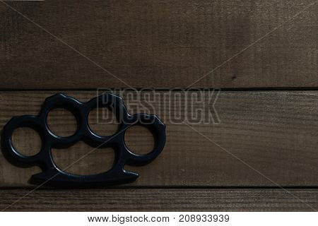 Brass knuckles on a beautiful brown wooden background.