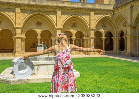 Freedom woman with open arms at old Coimbra Cathedral cloister. Se Velha de Coimbra is one of most important romanesque buildings in Portugal. Female tourist enjoying in university town of Coimbra.