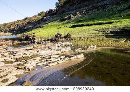 Dry river with dead fishes and dirty water. Portomarin Spain.