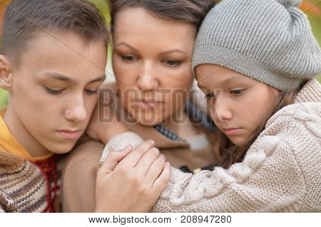 Portrait of sad mother and children in autumnal park