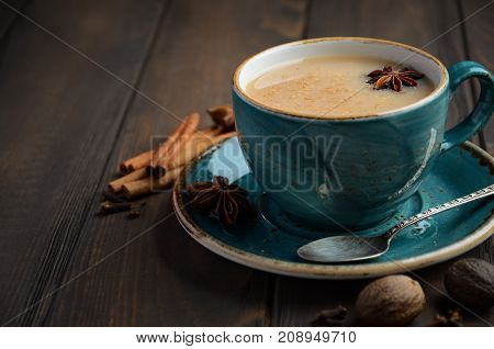 Indian masala chai tea. Spiced tea with milk on dark  wooden background.