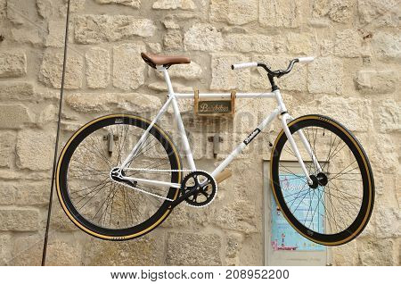 BESALU, SPAIN - JULY 26, 2017: White bike on stone wall in Besalu a medieval town of Girona Catalonia Spain.
