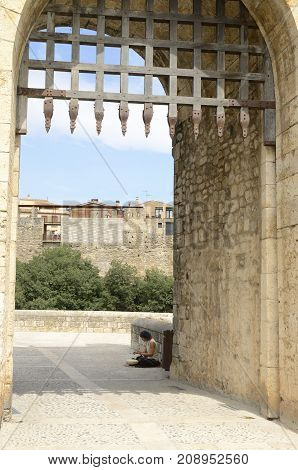 BESALU, SPAIN - JULY 26, 2017: Woman playing a musical instrument at the entrance of Besalu a medieval town of Girona Catalonia Spain.