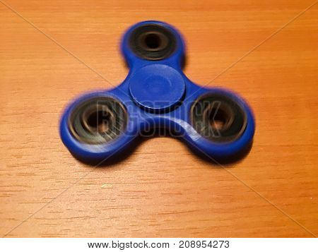 Spinner isolated on wood background. Blue toy spinner. Hand spinner isolated on wooden background. Toy spiner spinner
