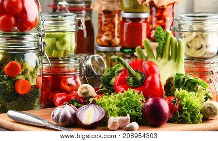 Jars With Marinated Food And Raw Vegetables On Cutting Board