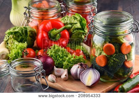 Jars With Marinated Food And Raw Vegetables On Cutting Board