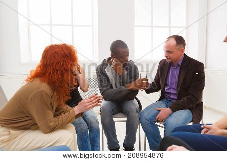 Meeting of support group. Depressed african-american man sitting at rehab group therapy. Psychotherapy, depression, life issues concept