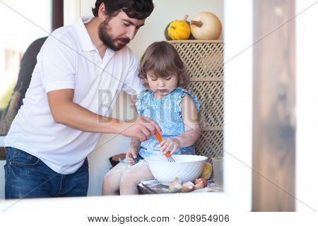 Caucasian family of single father and child cooking in the kitchen whisking eggs baking apple pie family leisure time homemade baking. Adult teaches little kid how to cook.