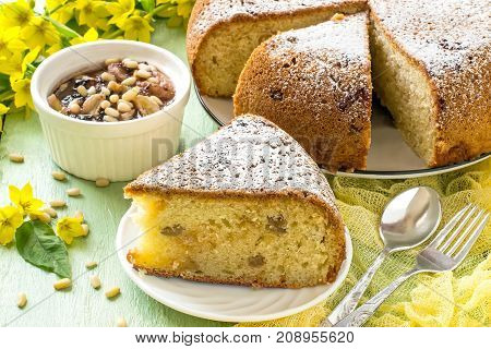 Delicious homemade pie with ricotta marshmallow and raisins banana dessert with chocolate marshmallow siberian pine nuts. Served in white dish on green wooden background with yellow gauze napkin