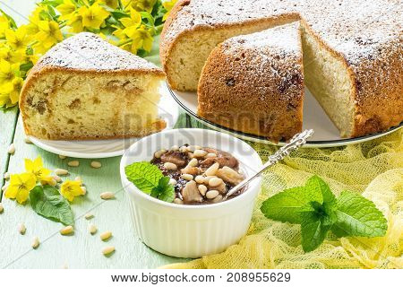 Delicious homemade pie with ricotta marshmallow and raisins banana dessert with chocolate marshmallow siberian pine nuts. Served in white dish on green wooden background with yellow gauze napkin