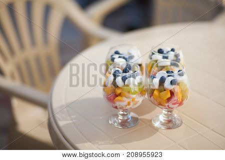 Fruit salad in a glass cup on a table in caffee house.