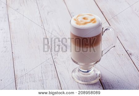 Delicious cappuccino on plank wooden table with copy space