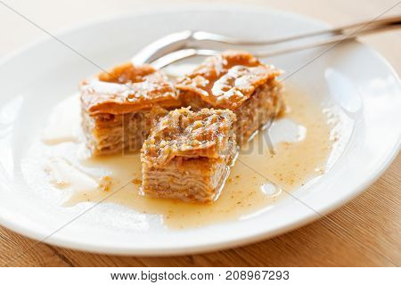 Traditional baklava and syrup served on white plate