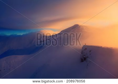 Fantastic scenery with a free rider and mountaineer high mountains in snow and the fog with interesting colour from the sun in the winter day.
