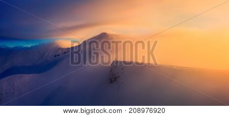 Unbelievable sunrise high at the mountains covered by snow. The free rider guy with the up raised hands is staying at the edge enjoying the scenery.