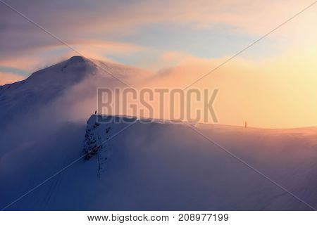 Unbelievable sunrise high at the mountains covered by snow. The free rider guy with the up raised hands is staying at the edge enjoying the scenery.