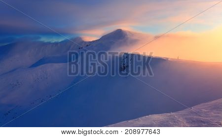 High in the mountains the sun is rising and enlightens everything with wonderful orange color. The mountains are in snow. Unbelievable winter landscape.