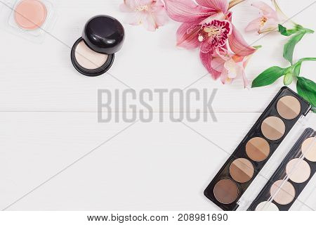 Decorative flat lay composition with makeup products, cosmetics and flowers. Flat lay, top view on wooden background. Copytext