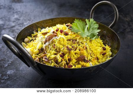 Indian vegetarian biryani with nuts and raisins as close-up in a korai 